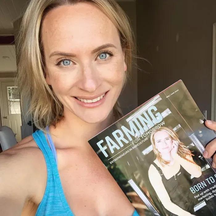 Lynn Dargis with a smile on her face holding an issue of Farming for Tomorrow magazine with her on the cover.