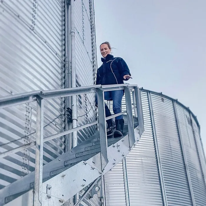 Lynn Dargis climbing down a ladder in the barn.